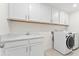 A bright laundry room with white cabinetry, sink, and modern washer and dryer at 652 Marion Hills Way, Knightdale, NC 27545
