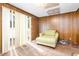 Living room featuring vertical blinds, a comfortable lounge chair, and wood-paneled walls at 722 Forge Rd, Durham, NC 27713