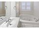 Bright bathroom with soaking tub, window and vanity with sink at 8209 Rolling Glenn Dr, Raleigh, NC 27616