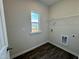 An empty laundry room is shown with a window, dark wood-style vinyl flooring and laundry connections at 83 Commons Cir # 236, Clayton, NC 27520