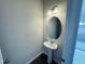 A powder room features a pedestal sink and a round mirror under a 2-bulb lighting fixture at 83 Commons Cir # 236, Clayton, NC 27520