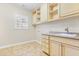 Laundry room with cabinets, sink, a window, and neutral-colored tile floors at 2012 Wide River Dr, Raleigh, NC 27614