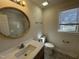 A bathroom featuring a single sink vanity with round mirror, window, and shower-tub combo at 208 Lawrence Rd, Cary, NC 27511
