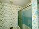 A bathroom with floral wallpaper and a blue-tiled shower-tub combo at 2118 N Woodland Rd, Henderson, NC 27536