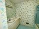 Bathroom with floral wallpaper, single vanity, and shower-tub combo at 2118 N Woodland Rd, Henderson, NC 27536