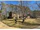 Brick house with mature trees, offering a shaded yard and a glimpse of the neighborhood surroundings at 2118 N Woodland Rd, Henderson, NC 27536