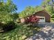 Side view of a brick home featuring an attached garage, blooming bushes, and a well-maintained lawn and driveway at 2118 N Woodland Rd, Henderson, NC 27536