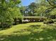 Traditional brick home with a lush green lawn and mature trees providing shade and curb appeal at 2118 N Woodland Rd, Henderson, NC 27536