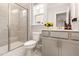 Well-lit bathroom featuring tiled shower, gray vanity, and modern fixtures with a window above the toilet at 2212 Jollay St, Durham, NC 27703