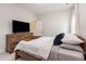 Well-lit bedroom featuring a bed with plush pillows and a wooden dresser with a modern TV at 2212 Jollay St, Durham, NC 27703