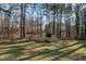 View of the spacious backyard featuring a storage shed, fenced-in yard, and many trees at 2520 Summit Ln, Creedmoor, NC 27522