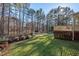 View of the spacious backyard featuring a fenced-in yard, deck, storage shed, and many trees at 2520 Summit Ln, Creedmoor, NC 27522