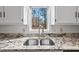Kitchen with stone countertops, stainless steel sink, and a window overlooking wooded backyard at 2520 Summit Ln, Creedmoor, NC 27522