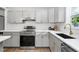 A modern kitchen featuring stainless steel appliances, gray cabinets, white subway tile backsplash, and quartz countertops at 318 Holland Glen St, Fuquay Varina, NC 27526