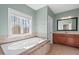 Bright bathroom featuring a large soaking tub, a window with a view, and neutral tilework at 504 Crooked Pine Dr, Cary, NC 27519
