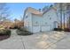 Spacious three-car garage featuring white doors and an extra-wide driveway nestled among trees and bushes at 504 Crooked Pine Dr, Cary, NC 27519