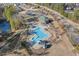 Aerial view of a community pool with ample seating, clubhouse, and playground near a scenic lake and parking at 504 Crooked Pine Dr, Cary, NC 27519