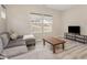 Cozy living room featuring wood floors, a gray sectional sofa, and a media center with a TV at 5439 Ripplebrook Rd, Durham, NC 27712