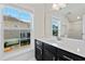 Modern bathroom featuring a dark vanity, quartz countertop, and window view at 5501 Advancing Ave, Raleigh, NC 27616