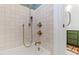 Close-up of white tiled shower and antique brass hardware next to a green painted vanity at 6532 Wakefalls Dr, Wake Forest, NC 27587