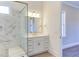 Bright bathroom featuring a marble tiled shower with glass enclosure, vanity with gold hardware, and open doorway at 75 Harvest View Way, Franklinton, NC 27525