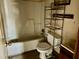 Outdated bathroom with tiled shower-tub combo, toilet and metal shelving unit at 750 David St, Henderson, NC 27536