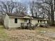 Modest single story duplex style home with wooden porch and bare trees in background at 750 David St, Henderson, NC 27536