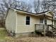 Side view of single story home with weathered siding, small porch and overgrown lawn at 750 David St, Henderson, NC 27536
