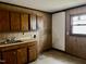 View of an outdated kitchen with laminate cabinets, sink, and a window overlooking the yard at 750 David St, Henderson, NC 27536