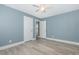 This bedroom features blue walls, light wood floors, a ceiling fan, and a closet at 7722 Nc 27 W, Lillington, NC 27546