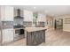 Bright kitchen featuring white cabinets, stainless steel appliances, island and stylish gray wood flooring at 7722 Nc 27 W, Lillington, NC 27546
