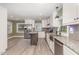 Bright kitchen featuring white cabinets, stainless steel appliances, island, and stylish gray wood flooring at 7722 Nc 27 W, Lillington, NC 27546