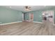 Spacious living room featuring stylish gray wood flooring, calming light green walls, and access to kitchen at 7722 Nc 27 W, Lillington, NC 27546