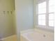 This bathroom features a white tiled bathtub, a window and 4 hooks for hanging towels at 8 Weeping Beech Way, Durham, NC 27713