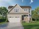 Charming two-story home with a two-car garage, welcoming entrance, and manicured lawn and beautiful landscaping at Lot 14 Grayhaven Pl, Raleigh, NC 27606