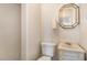 Cozy bathroom featuring a toilet, sink, and tiled shower with neutral-toned walls and a unique mirror at 10611 Quail Roost Rd, Bahama, NC 27503