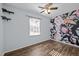 Bedroom with floral accent wall, wood-look floors, ceiling fan, and a bright window at 1195 Champion Dr, Cary, NC 27511