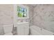Updated bathroom with a single vanity, marble styled tile, and a window for natural light at 1411 Rosewood St, Durham, NC 27701