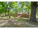 Quaint brick home nestled among mature trees on a spacious lot, surrounded by greenery at 1411 Rosewood St, Durham, NC 27701