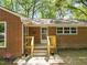 Inviting front porch with wooden railing, brick exterior, and security system sign at 1411 Rosewood St, Durham, NC 27701