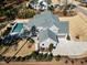 Drone shot showcases a gray home with a pristine pool, stone patio and lush landscaping at 1520 Grand Willow Way, Raleigh, NC 27614