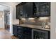 Elegant bar area features dark cabinetry with glass fronts, granite counters, and a beverage fridge at 1520 Grand Willow Way, Raleigh, NC 27614