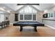 Entertaining game room features a pool table, hardwood floors, and large triangle window at 1520 Grand Willow Way, Raleigh, NC 27614