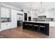 A spacious kitchen featuring white cabinets, stainless steel appliances, dark island with seating and hardwood floors at 1520 Grand Willow Way, Raleigh, NC 27614