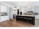 A spacious kitchen featuring white cabinets, stainless steel appliances, dark island with seating and hardwood floors at 1520 Grand Willow Way, Raleigh, NC 27614