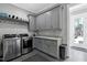 Well-equipped laundry room with gray cabinetry, granite countertops, and stainless steel appliances at 1520 Grand Willow Way, Raleigh, NC 27614