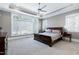 Serene main bedroom featuring large windows, neutral colors, and a tray ceiling with fan at 1520 Grand Willow Way, Raleigh, NC 27614