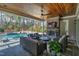 Cozy covered patio with stone fireplace, TV, ceiling fan, and plush seating, overlooking the pool at 1520 Grand Willow Way, Raleigh, NC 27614