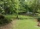 Lush backyard featuring a well-maintained lawn, mature trees, and a charming seating area with an arbor at 2001 Carrington Dr, Raleigh, NC 27615
