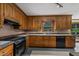 Kitchen with wood cabinetry, black appliances, neutral backsplash, and natural lighting at 2001 Carrington Dr, Raleigh, NC 27615